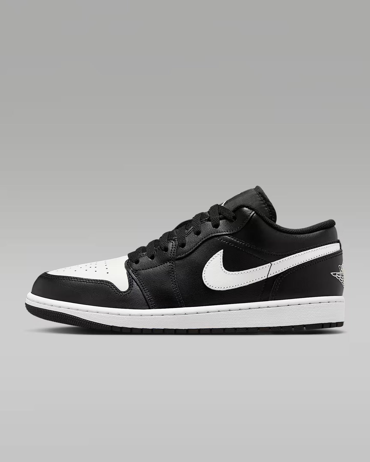 A pair of Nike Air Jordan 1 Low sneakers with a black and white color scheme.