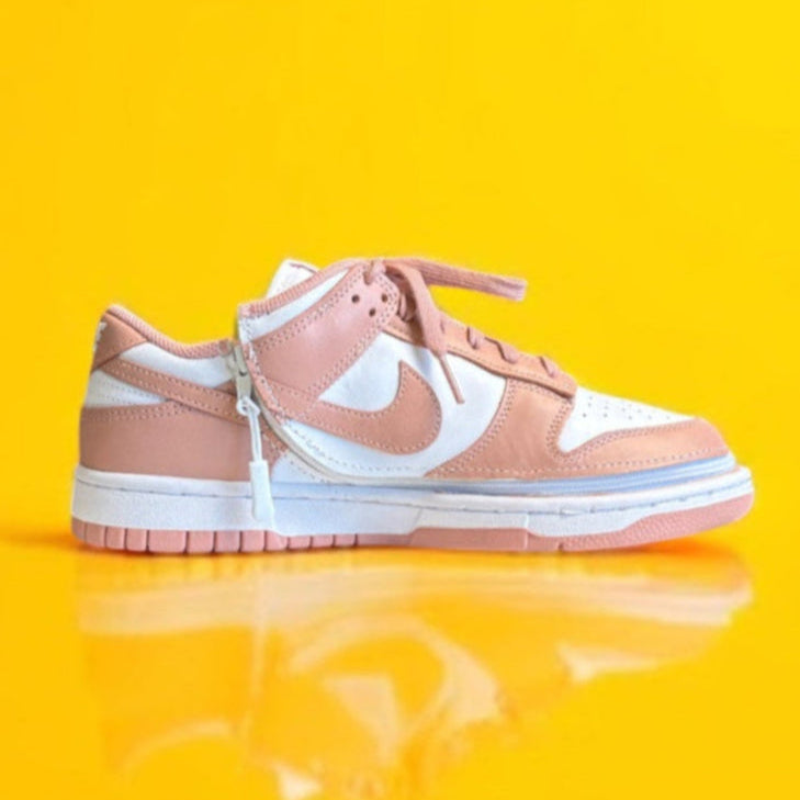 A pink and white Nike dunk low with a wrap around zipper on a yellow background