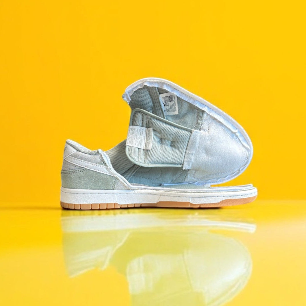 Green and white Nike dunk low with a zipper on a yellow background