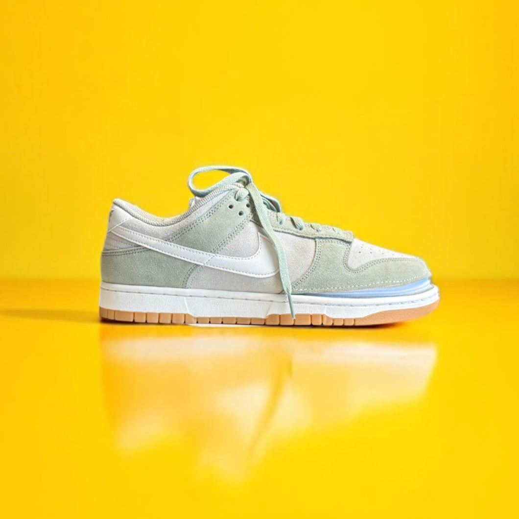 Green and white Nike dunk low with a zipper on a yellow background