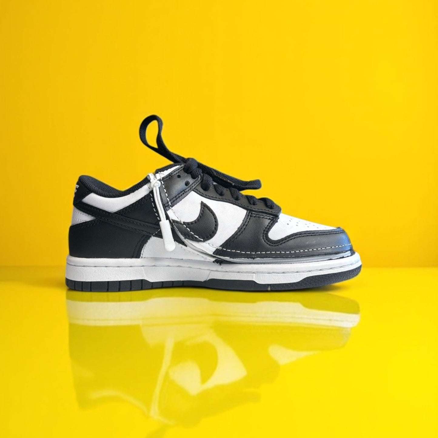 A pair of kids Zipped Nike white and black shoes with a zipper.