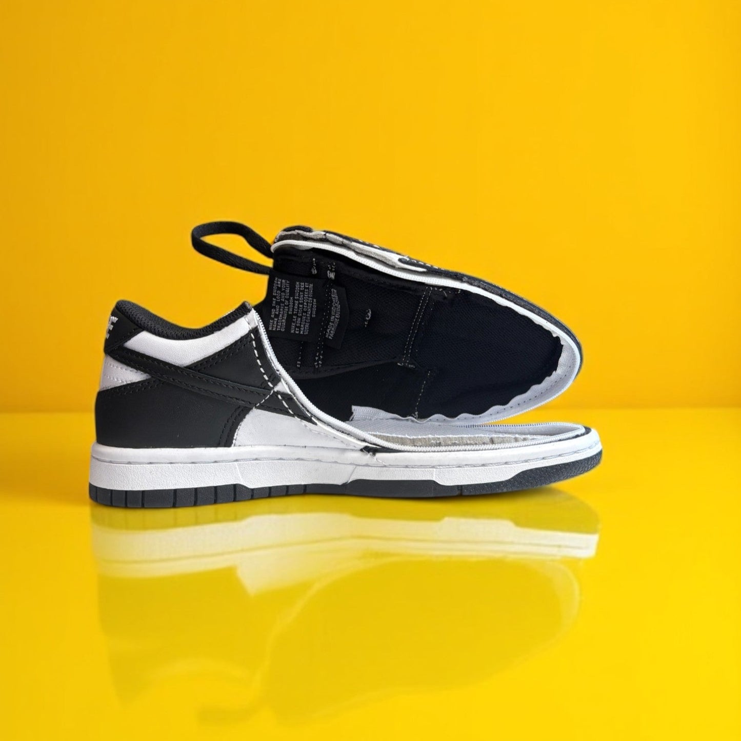 A pair of kids Zipped Nike white and black shoes with a zipper.