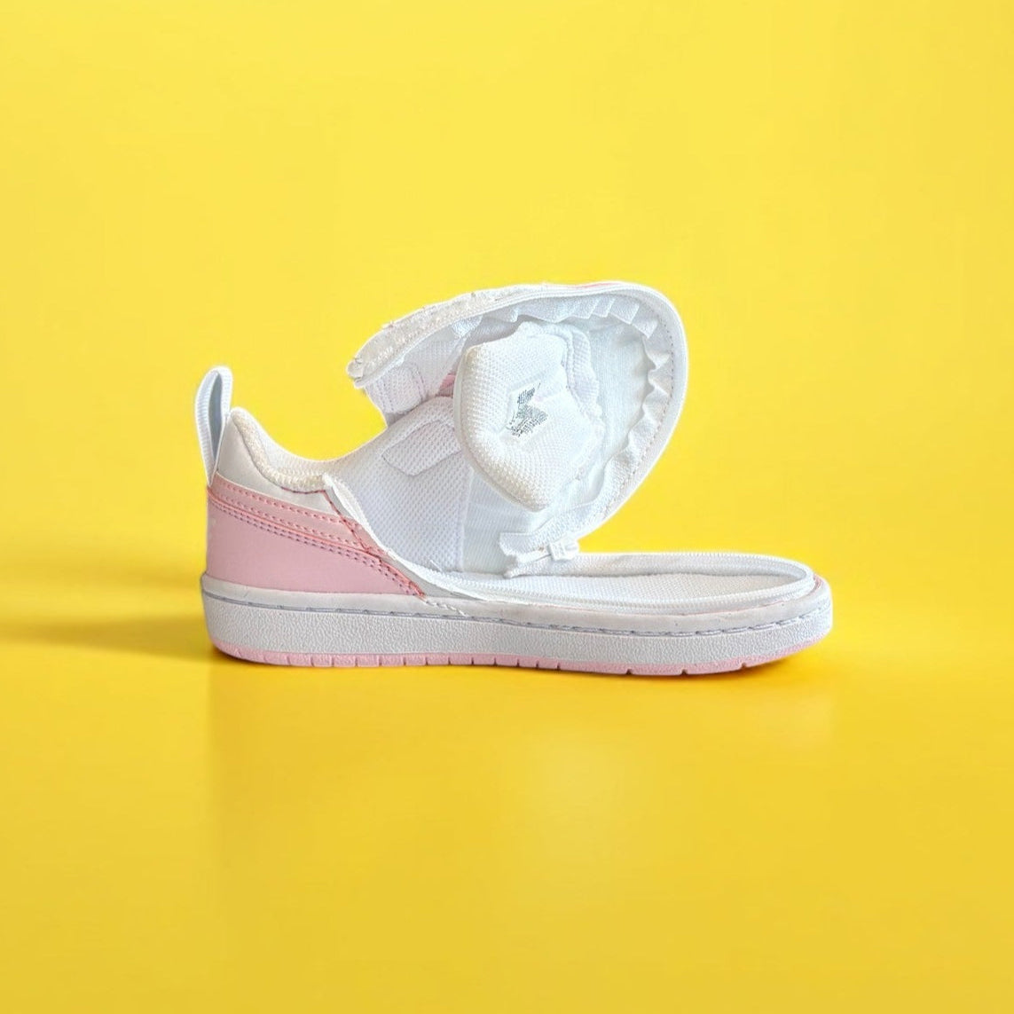 White and pink nike shoe with a zipper on a yellow background