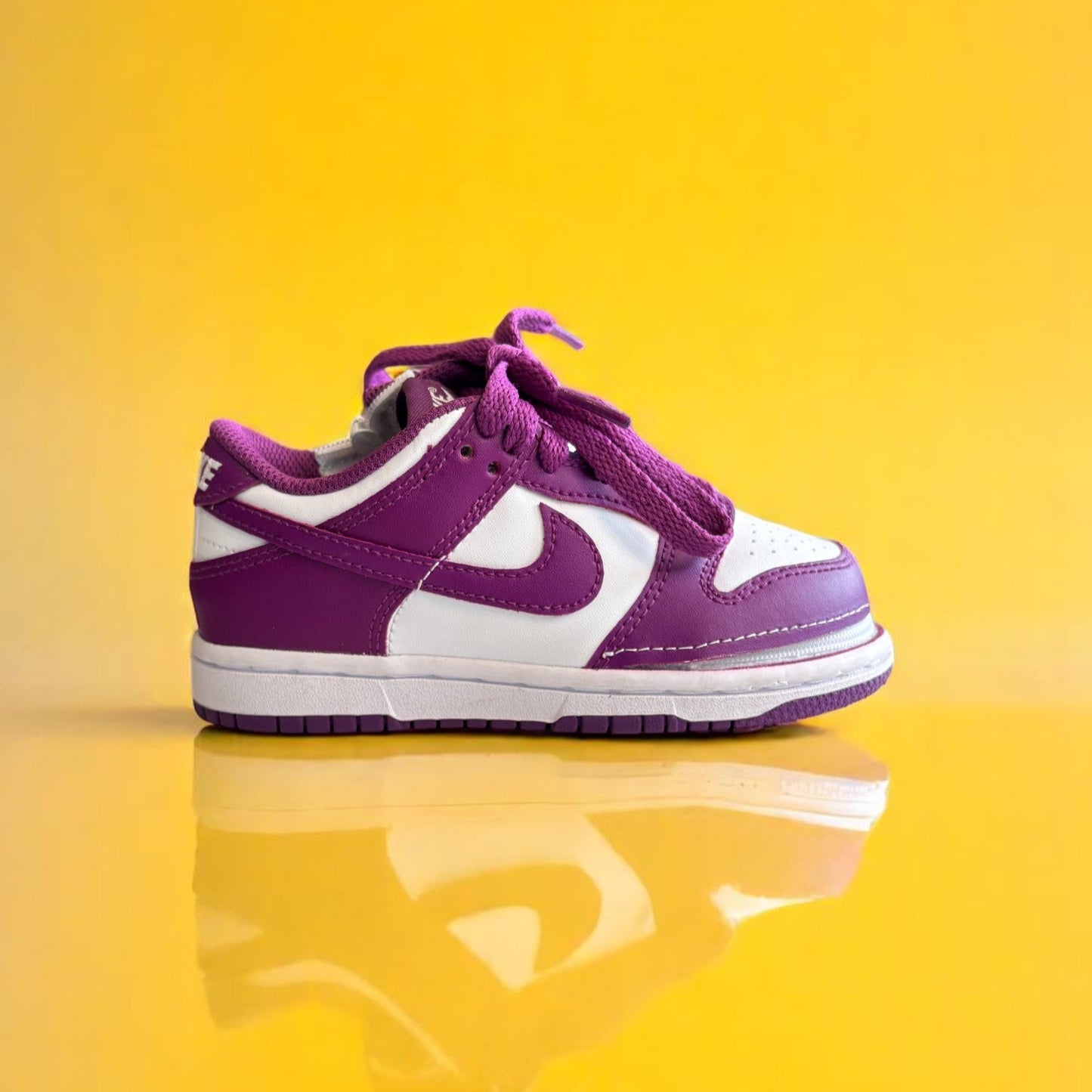 A pair of kids Zipped Nike white and purple shoes with a zipper.
