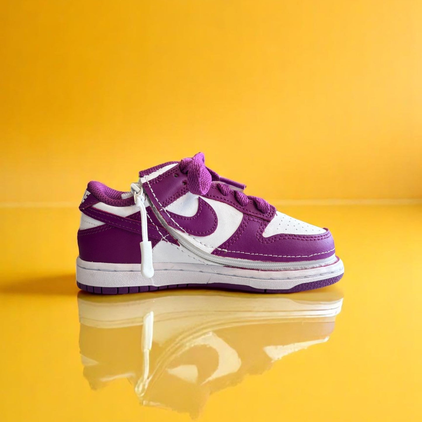A pair of kids Zipped Nike white and purple shoes with a zipper.