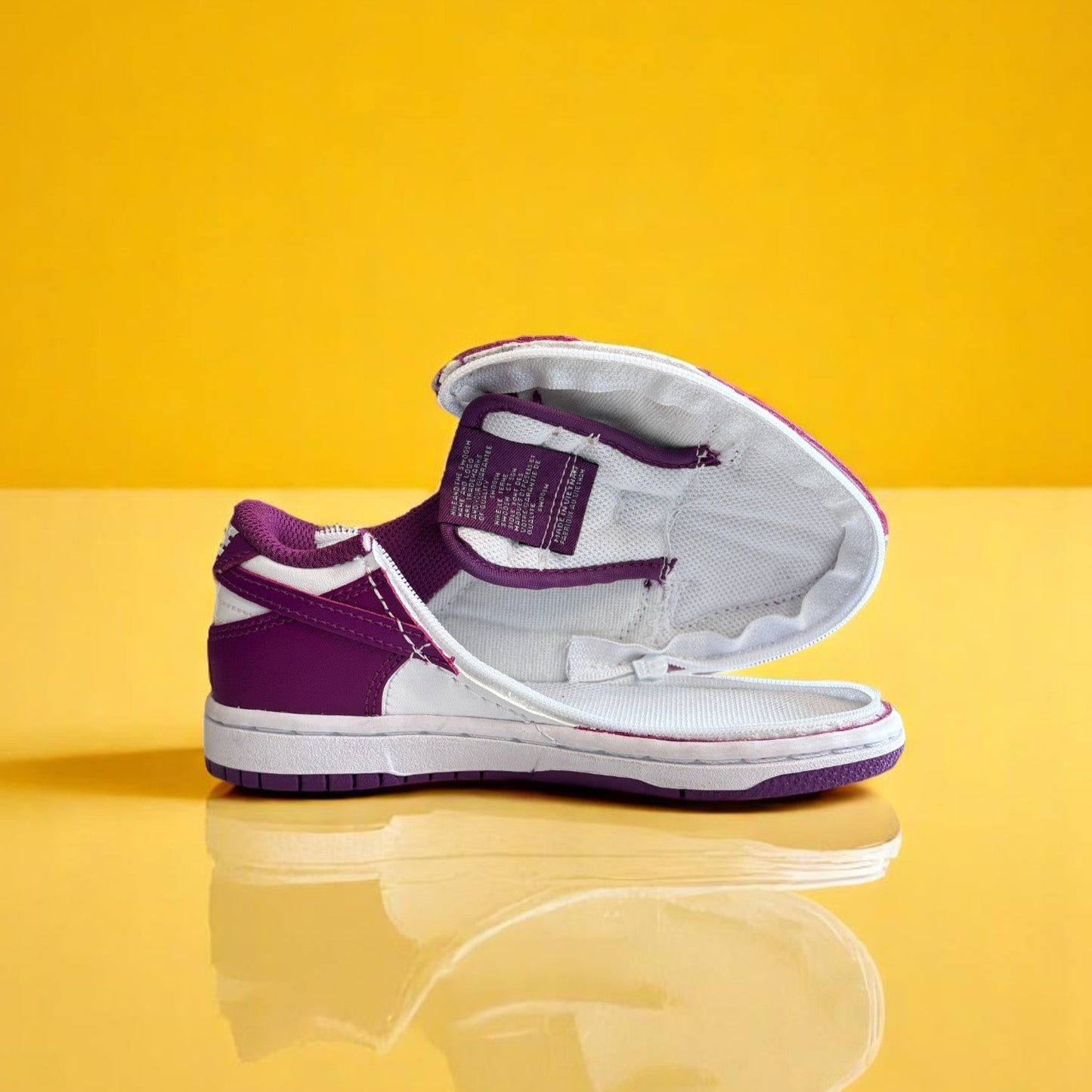 A pair of kids Zipped Nike white and purple shoes with a zipper.