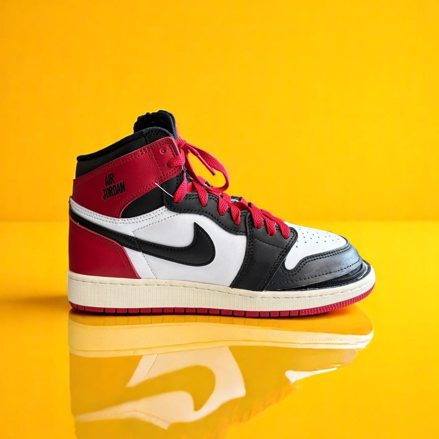 A red, black and white pair of Air Jordan 1 high tops with a zipper