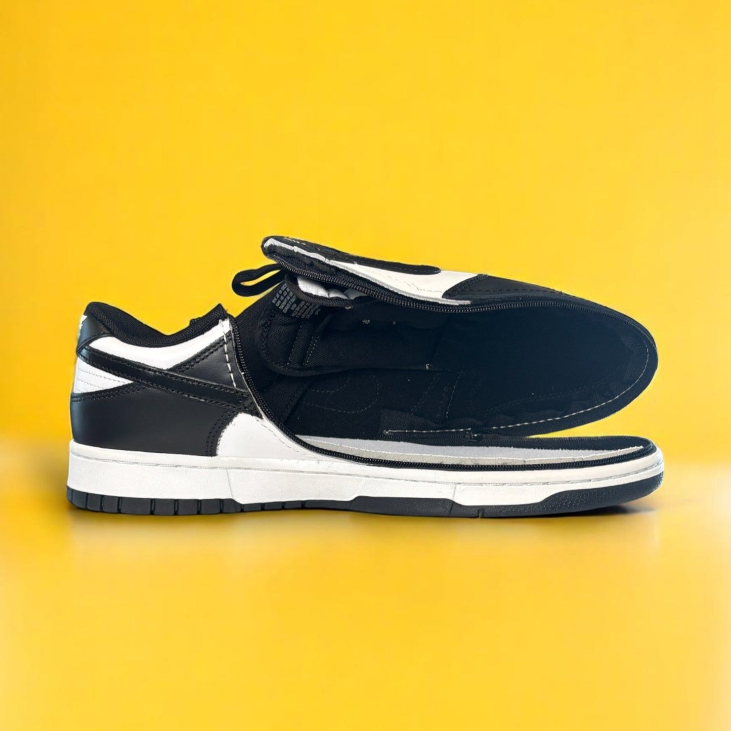 Black and white Nike dunk low with a zipper on a yellow background