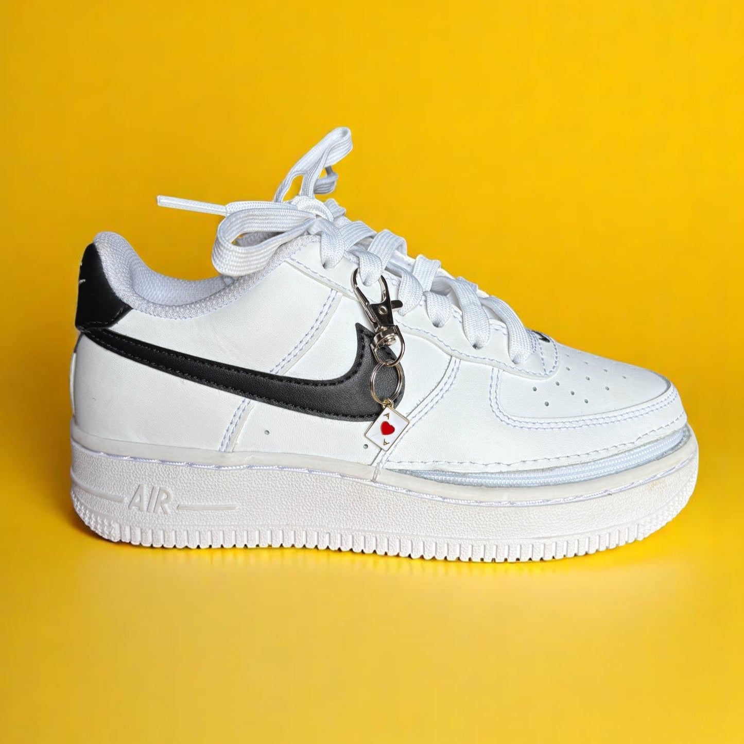 White sneaker with black swoosh logo on a yellow background