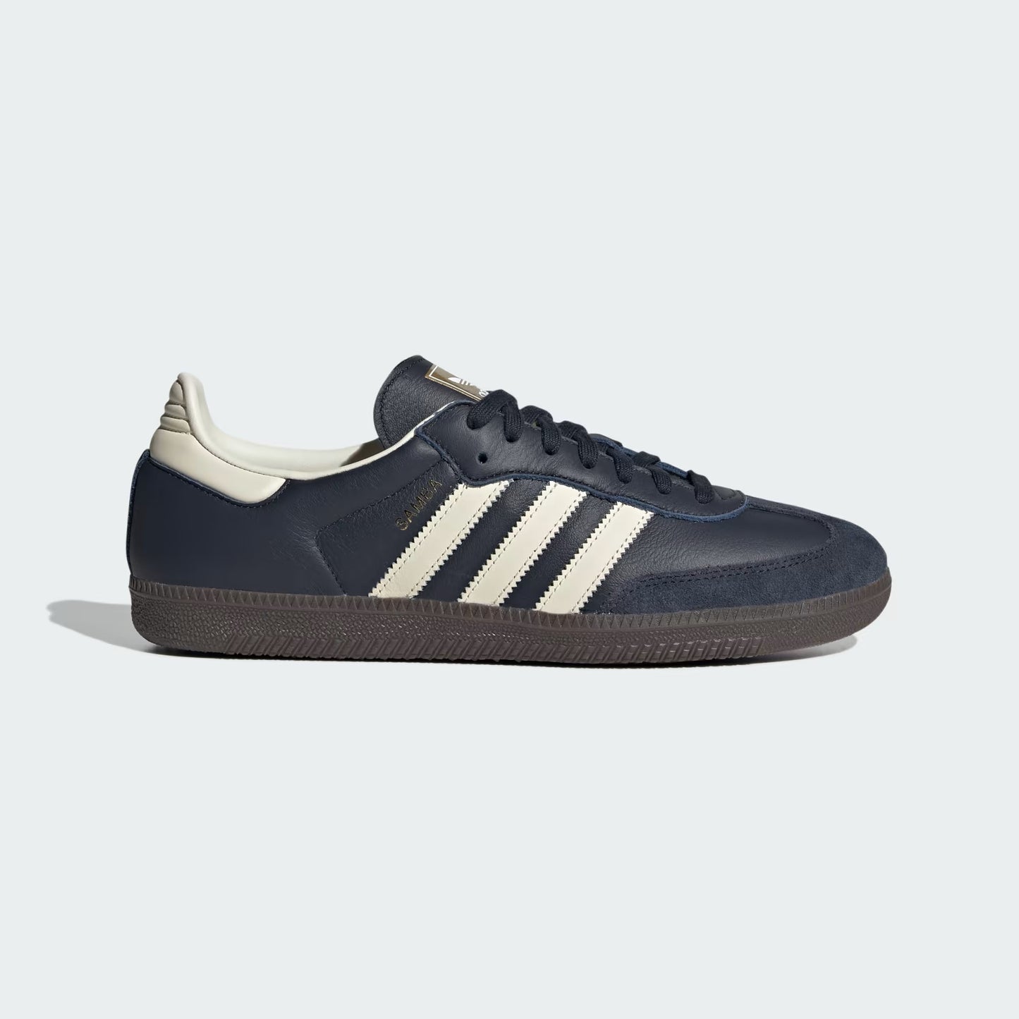 Navy blue Adidas sneaker with white stripes on a light gray background