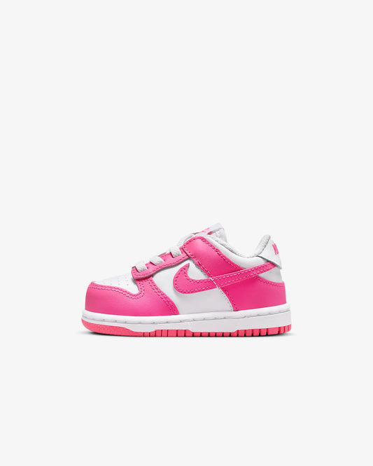A toddler-sized Nike Dunk Low sneaker in white and pink.